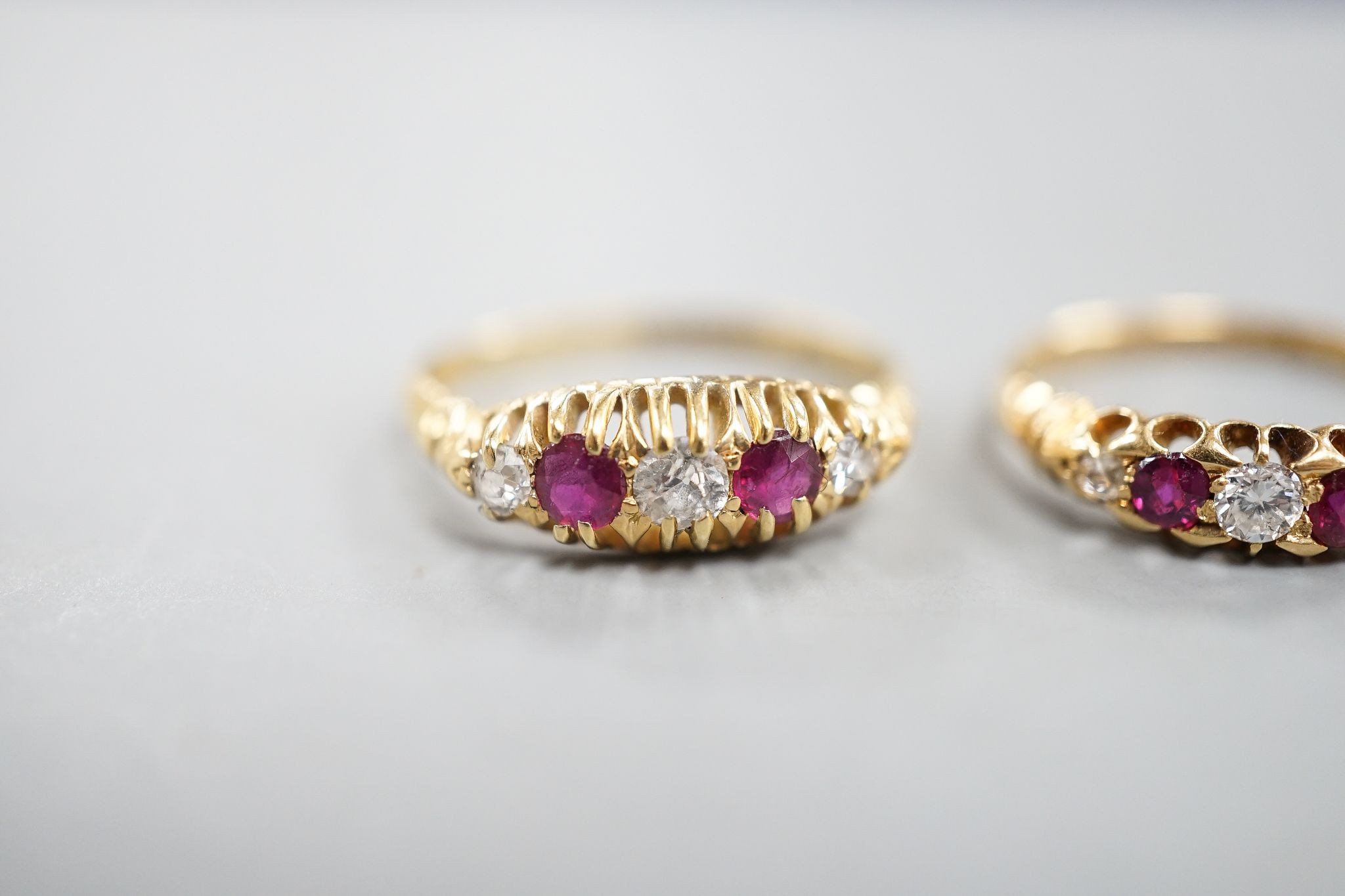 Two early 20th century 18ct gold, ruby and diamond five stone set half hoop rings, sizes m and P/Q, gross weight 5.1 grams.